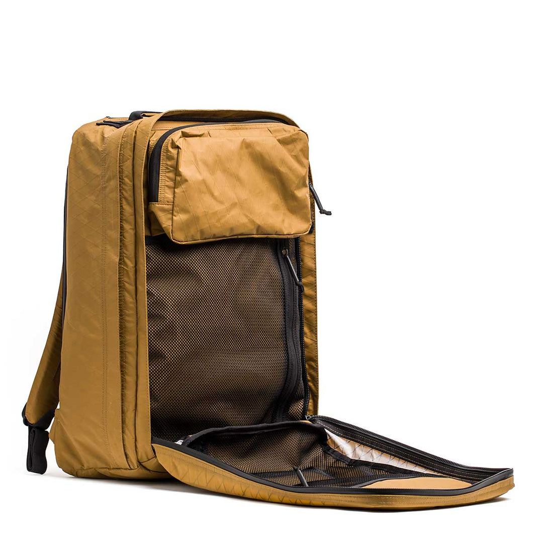 The GORUCK GR2 X-PAC brown waterproof travel backpack stands upright with its main compartment open, revealing mesh zip pockets and an organized interior.