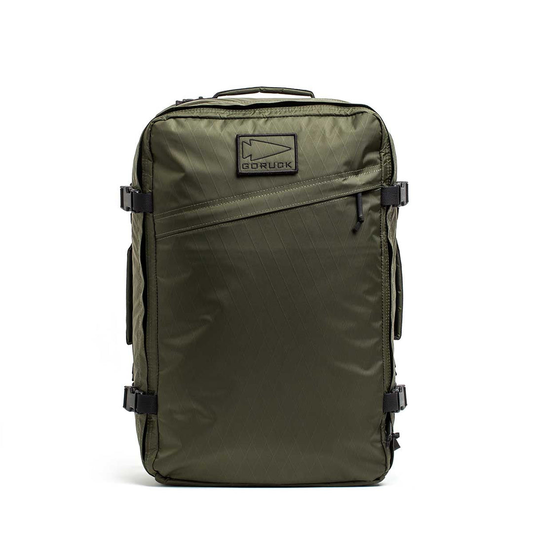 The GR3 - X-PAC is an olive green carry-on backpack featuring black zippers, handles, a front GORUCK logo patch, and waterproof material. Built for durability and covered by the Scars Lifetime Guarantee.