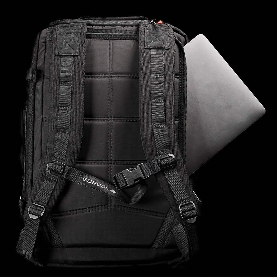 The GORUCK GR3 - Cordura is a sleek black travel backpack with waterproof zippers and a laptop partially tucked into the back pocket, displayed against a black background.