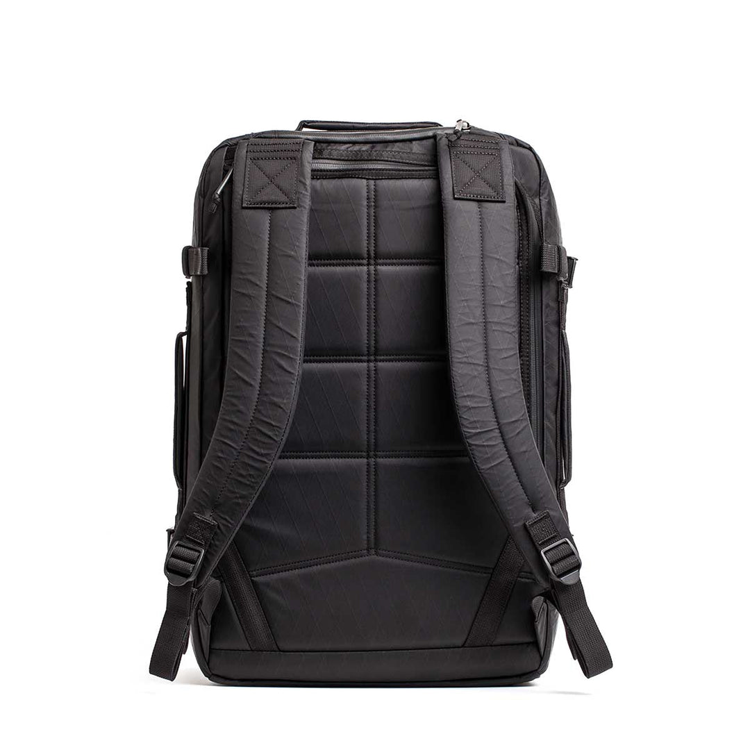 The GORUCK GR3 - X-PAC carry-on backpack is shown from the back with padded straps and back panel on a white background. Made from ultra-waterproof material, it comes with a lifetime guarantee for durability.