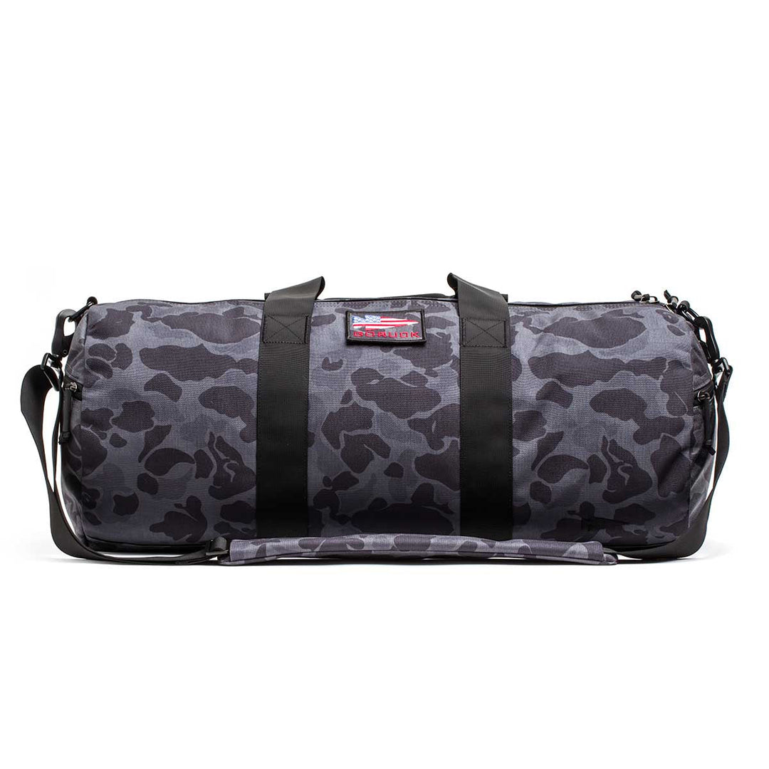 The Gym Bag - Cordura in gray with a black camo pattern features durable 1000D CORDURA fabric, black straps, a shoulder strap, and is displayed on a white background.
