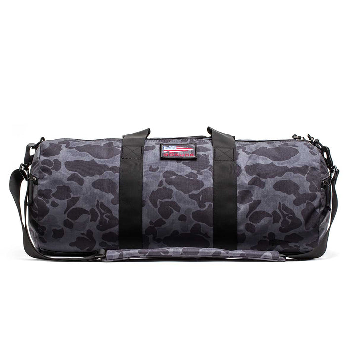 The Gym Bag - Cordura in gray with a black camo pattern features durable 1000D CORDURA fabric, black straps, a shoulder strap, and is displayed on a white background.