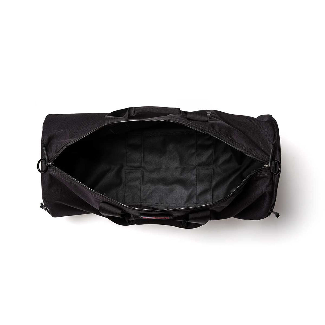 The Gym Bag - Cordura in black, made from durable 1000D CORDURA, is shown from above with its top zipper open, revealing a spacious, empty interior.