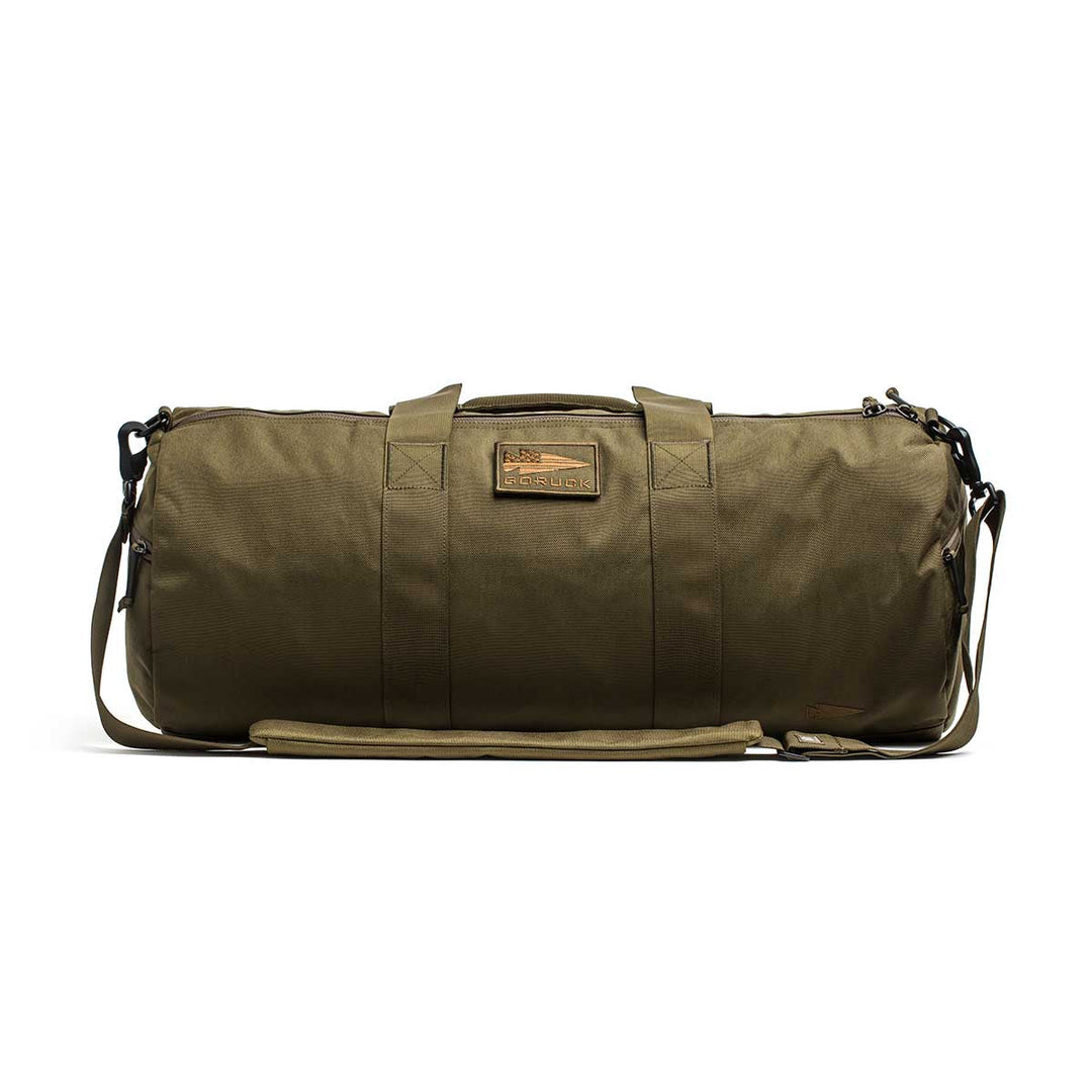 The Gym Bag - Cordura features olive green 1000D CORDURA fabric, sturdy handles, a shoulder strap, and a rectangular front patch.