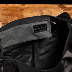 A black GORUCK Cordura gym bag, known for its durability, sits on a wooden surface with the interior label visible, showcasing the brand and 38L size details.