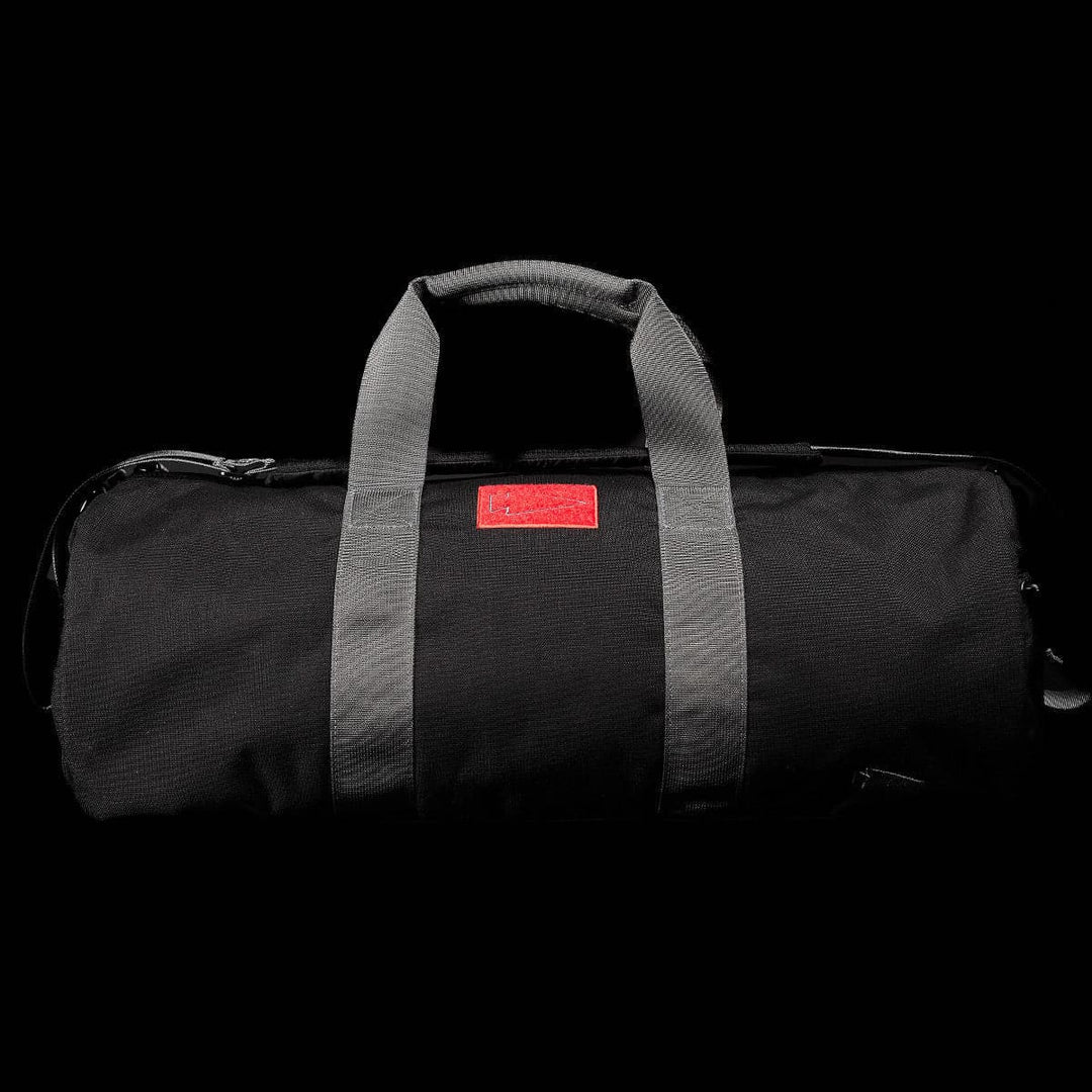 Introducing the GORUCK Gym Bag - Cordura: This stylish and resilient duffel gym bag combines a sleek black exterior with gray straps and a striking red logo tag. Crafted from durable CORDURA fabric, it boasts a 38L capacity, making it perfect for all your daily workout essentials.