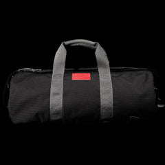 Introducing the GORUCK Gym Bag - Cordura: This stylish and resilient duffel gym bag combines a sleek black exterior with gray straps and a striking red logo tag. Crafted from durable CORDURA fabric, it boasts a 38L capacity, making it perfect for all your daily workout essentials.