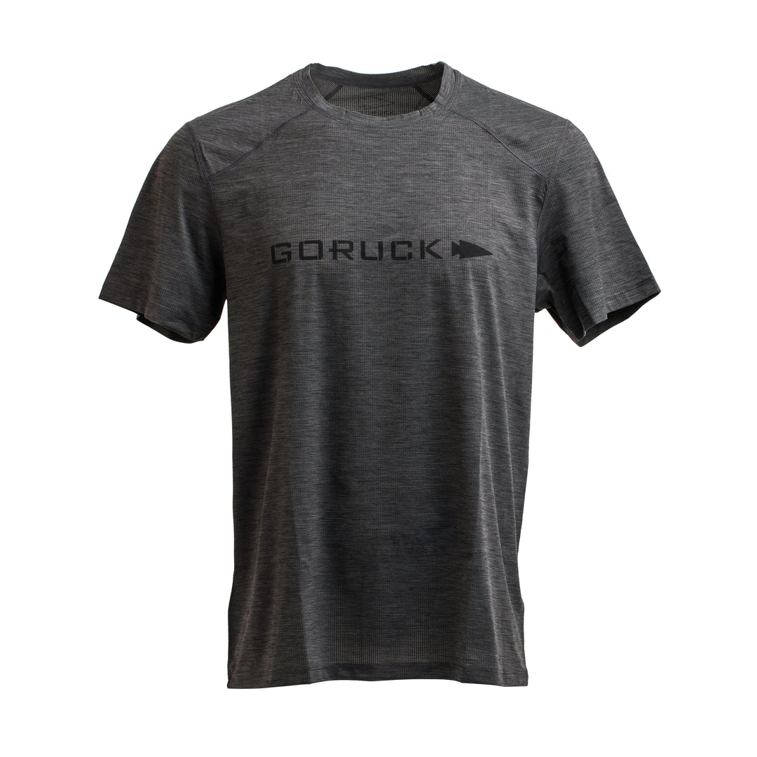 The GORUCK Men’s Performance Tee, made from ToughMesh™ fabric, comes in gray and features the word "GORUCK" and a right-pointing arrow printed in black on the chest. This lightweight training shirt has a straightforward design with short sleeves and a round neck, ideal for adventures ranging from urban environments to the Italian Alps.