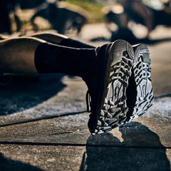 Close-up of a person’s Mackall 45 Black + Gum sneaker soles, showcasing their rugged durability as they exercise on a sunny outdoor pavement.