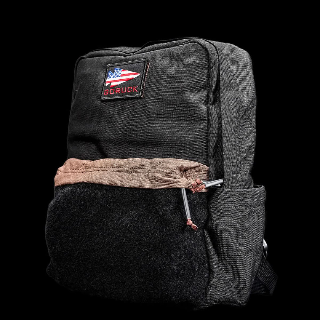 GORUCK's KR1 2.0 - Kid Ruck is a black kids backpack with reinforced stitching, showcasing an American flag patch and the "GORUCK" branding against a sleek black backdrop.