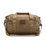 Kit Bag - Waxed Canvas by GORUCK: A tan duffel featuring a shoulder strap, leather accents, front zipper pocket, and a "GORUCK" patch on the front—designed in the classic style of an aviator's kit bag.