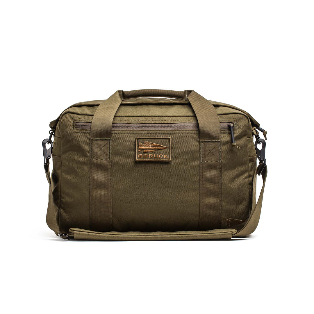 The GORUCK Kit Bag is an olive green messenger-style bag inspired by a Special Forces flight bag, featuring handles, a shoulder strap, and a front GORUCK logo patch.