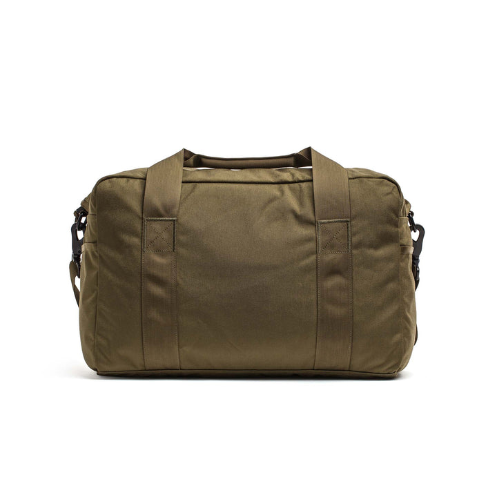 The GORUCK Kit Bag, styled in olive green with two handles and side straps, features a minimalist design inspired by classic aviator kit bags, displayed here against a white background.