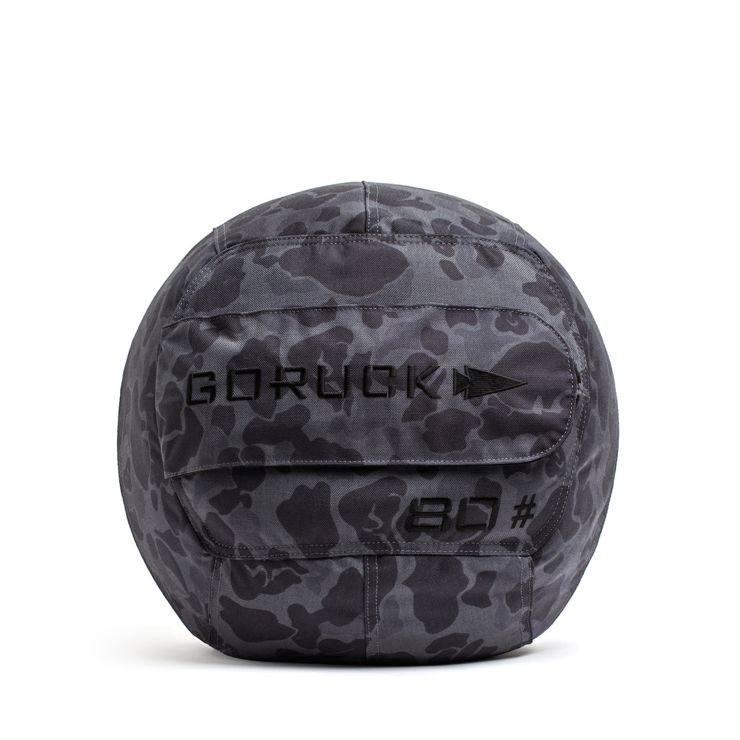 The GORUCK Sand Medicine Ball features a gray camo pattern with "GORUCK" and "20" printed on it—ideal for core stability workouts in your home gym.