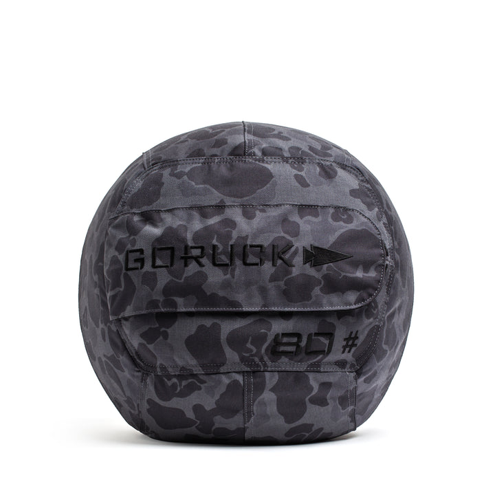 The GORUCK Sand Medicine Ball features a gray camo pattern with "GORUCK" and "20" printed on it—ideal for core stability workouts in your home gym.