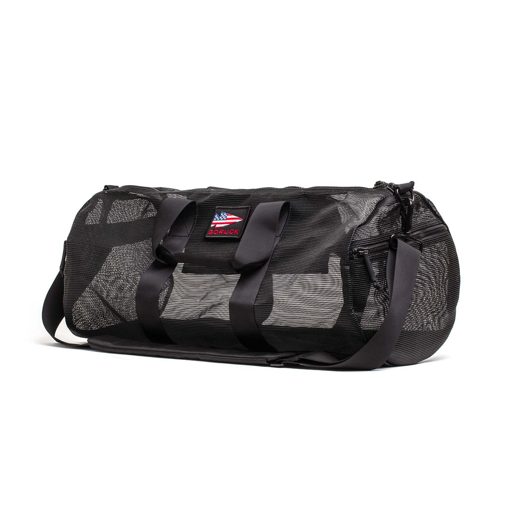 The Mesh Gym Bag features a shoulder strap, mesh panels for ventilation, and a small American flag patch on the front.