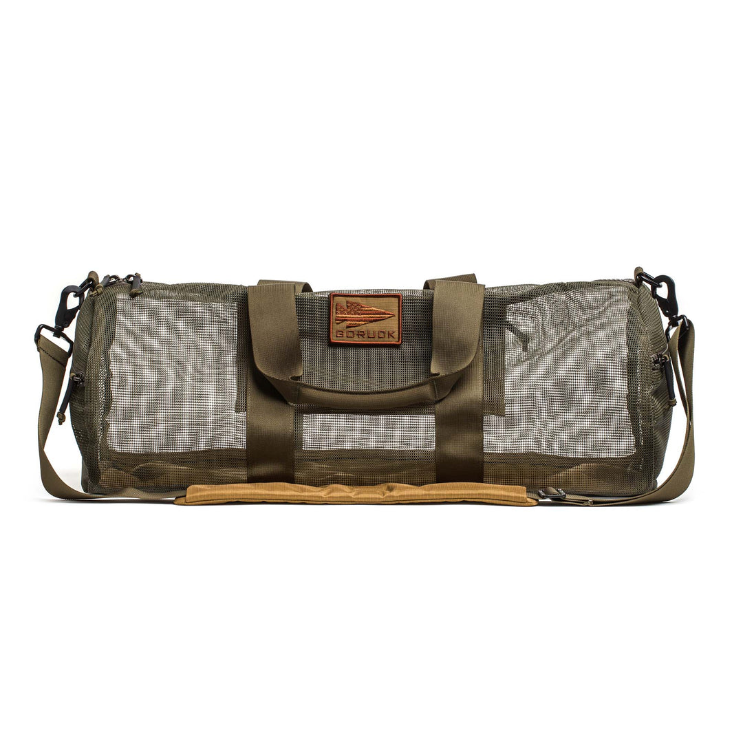The Mesh Gym Bag features olive green fabric, mesh sides, a shoulder strap, and a brown leather front patch—ideal for daily use or as your go-to performance gym bag.