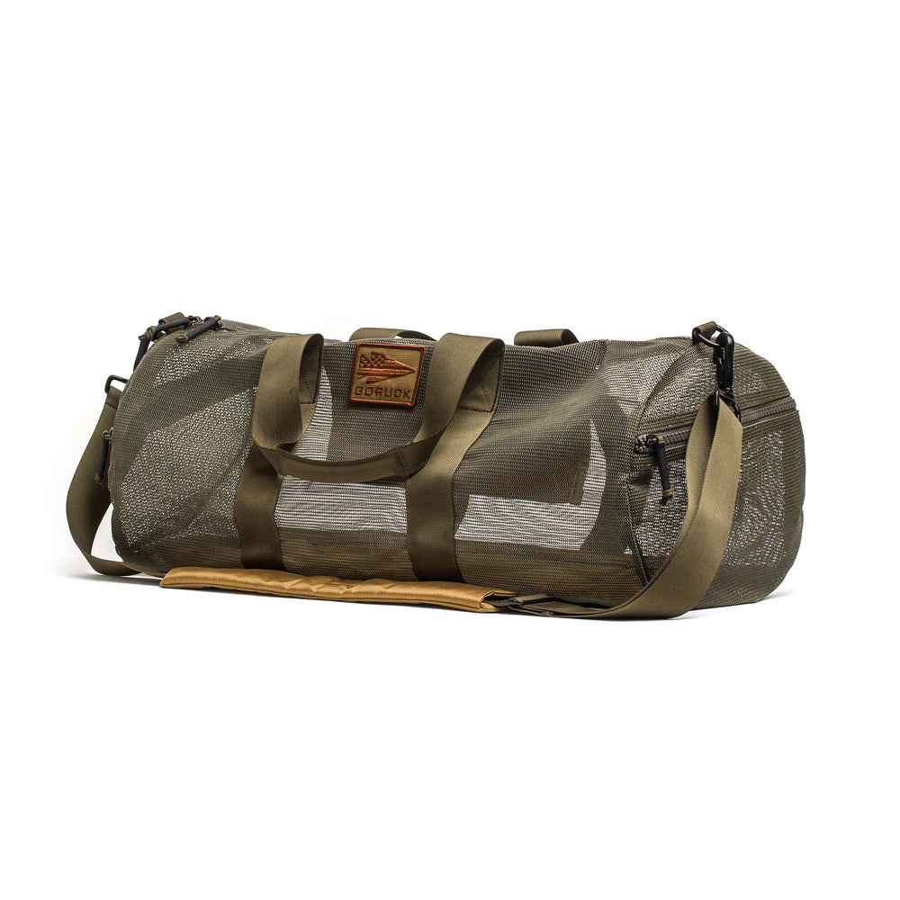 The Mesh Gym Bag in olive green features mesh panels, dual handles, a shoulder strap, and a leather patch on the front.