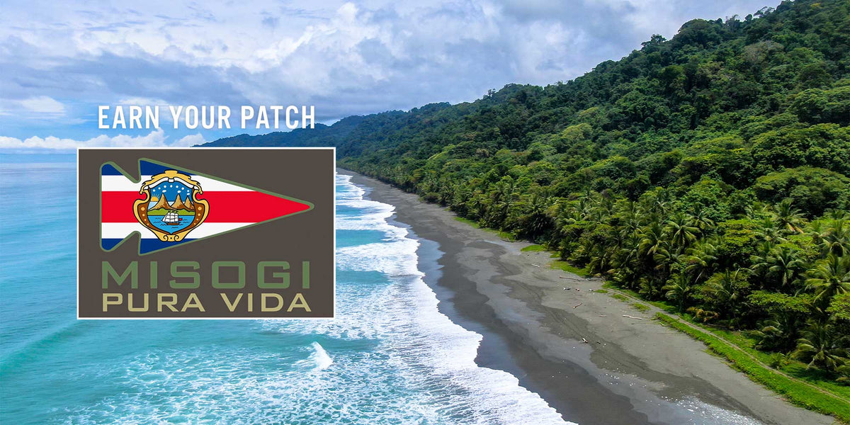 A tropical coastline with lush forest, waves, and a patch reading 