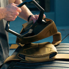 Person loading weighted plate into GORUCK rucking vest outdoors