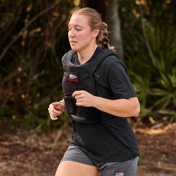 Woman running outdoors in GORUCK weighted vest and rucking gear, fitness training