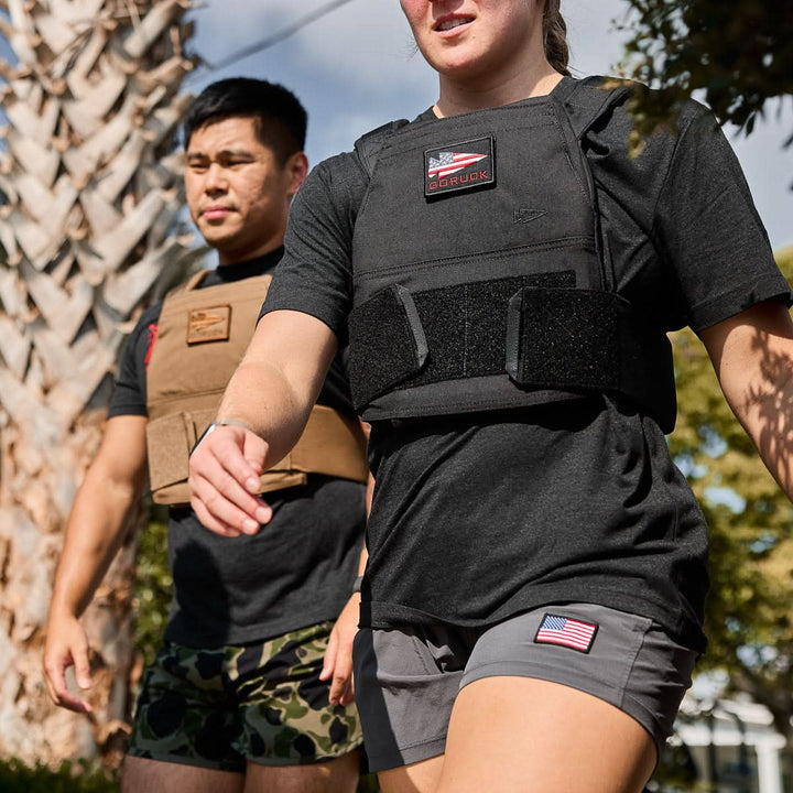 Two people wearing athletic clothing and Curved Ruck Plates walk outdoors under sunny skies.