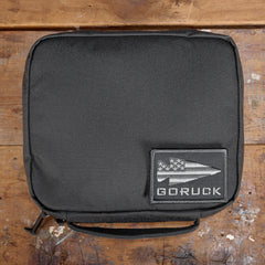 GORUCK padded field pocket in Armor Grey, displayed on wooden surface with GORUCK logo patch