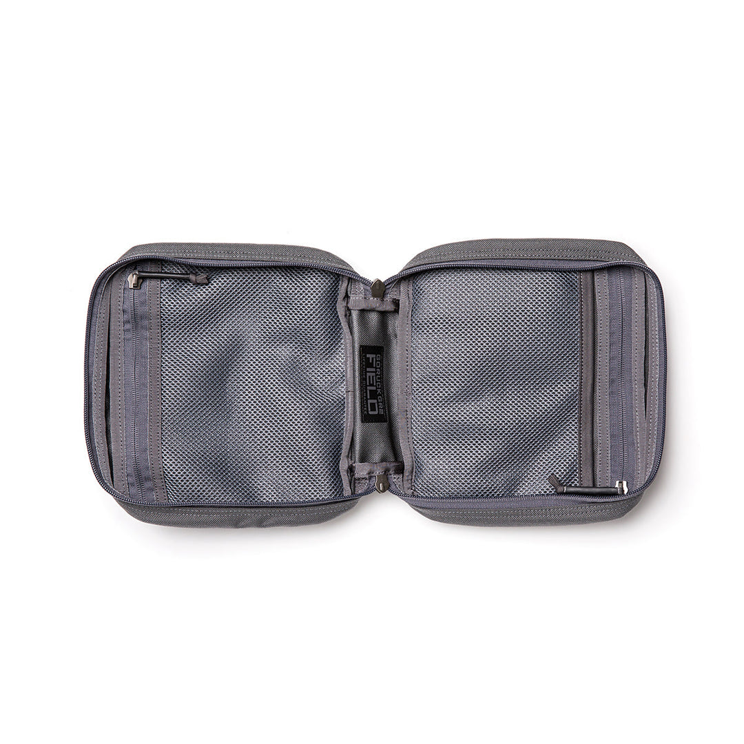 The GR2 Field Pocket is an open, gray travel pouch made from durable 1000D Cordura, featuring mesh compartments and zippers on each side.