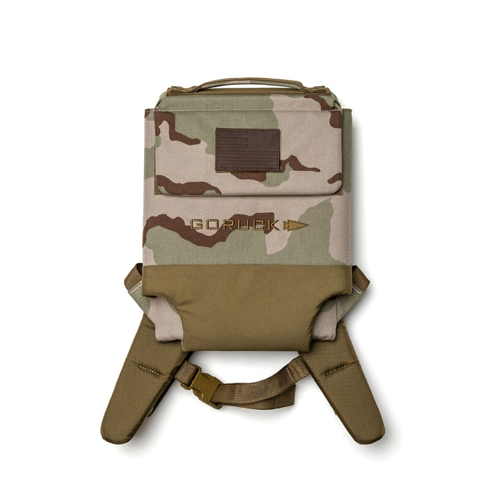 The GORUCK Ruck Plate Carrier 3.0 features a camouflage pattern, padded straps, ergonomic lumbar support, and an American flag patch on the front.