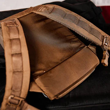 Brown padded backpack straps with stitched sections, lying open on a black surface.