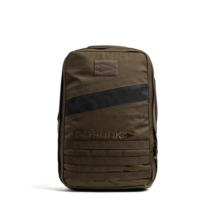 The GORUCK Rucker 4.0 is an olive green backpack with a black diagonal stripe, front "GORUCK" logo, and MOLLE webbing—ruggedly built for fitness training and ideal as a weighted rucksack.