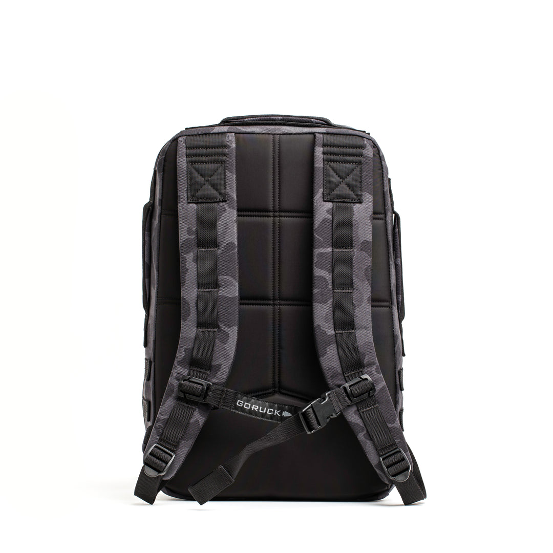 The GORUCK Rucker 4.0 is a black rucksack with padded straps and a subtle camo pattern, shown from the back on a white background—perfect for rucking adventures.