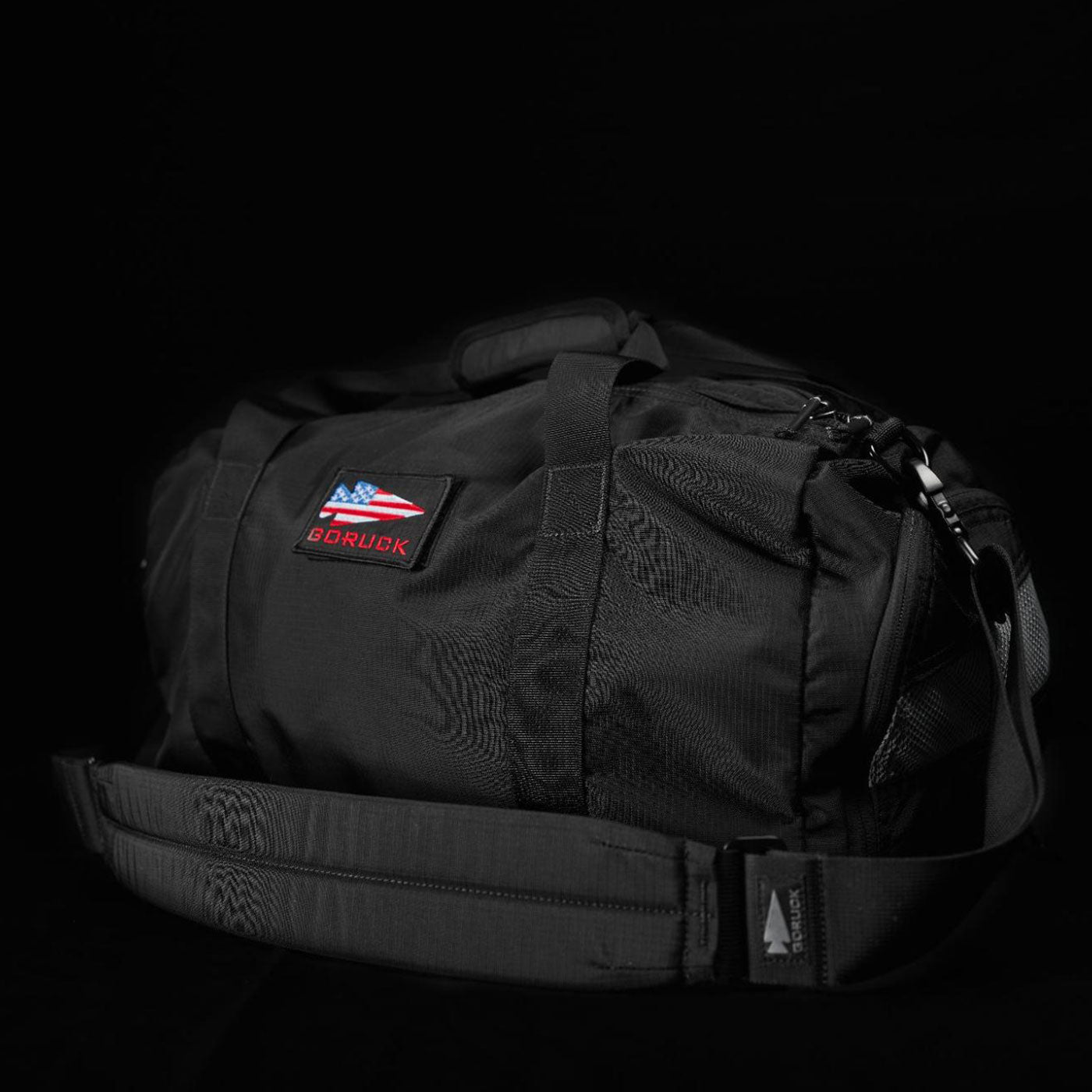 Black duffel bag with an American flag patch and “GORUCK” logo, displayed on a black background.
