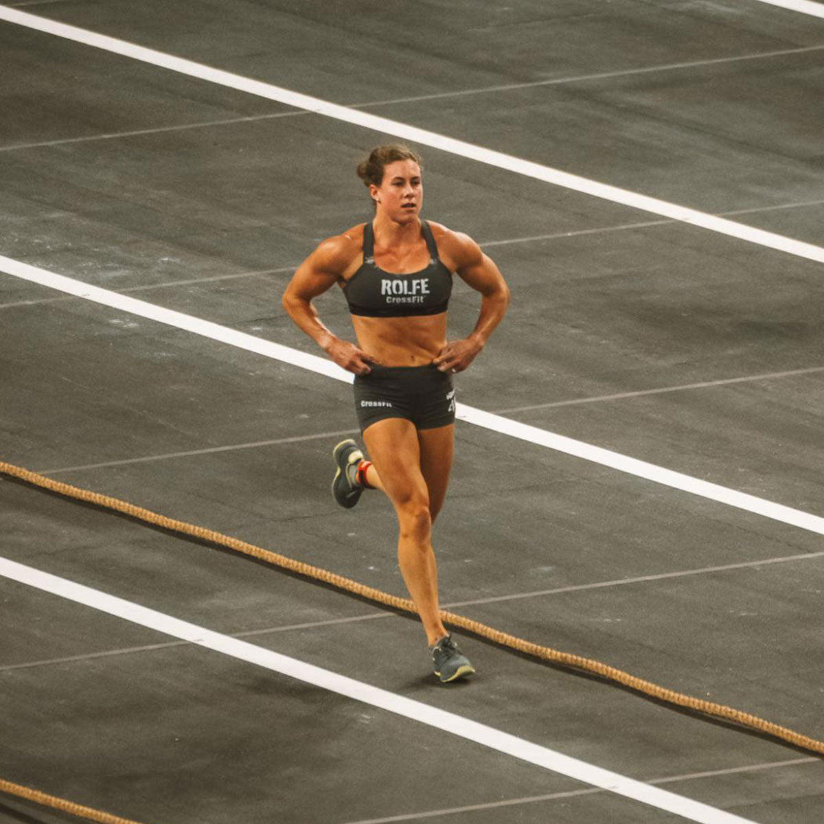 A female athlete in sportswear runs on a track during a competition.