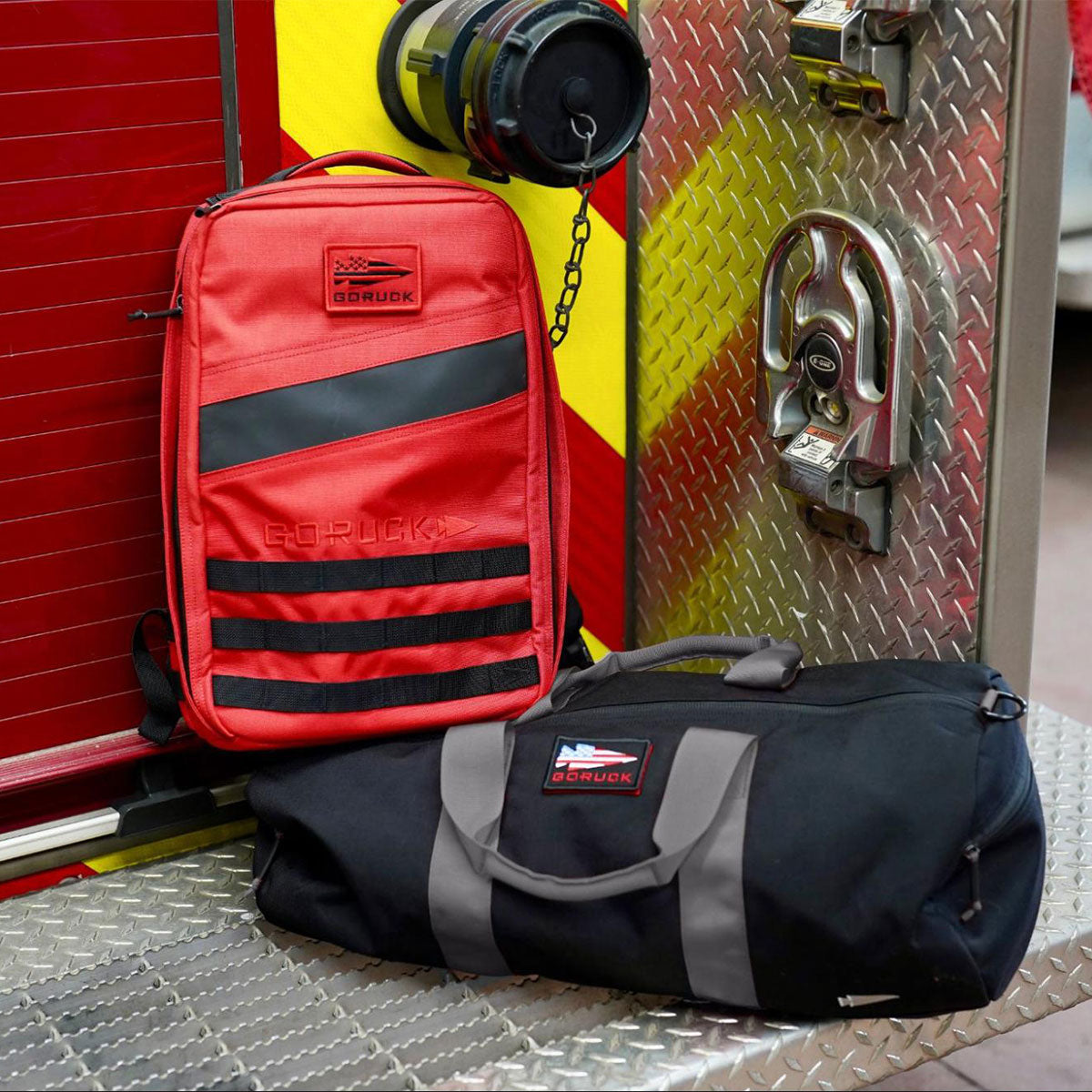 A red backpack and a black duffel bag sit on the metal step of a fire truck.