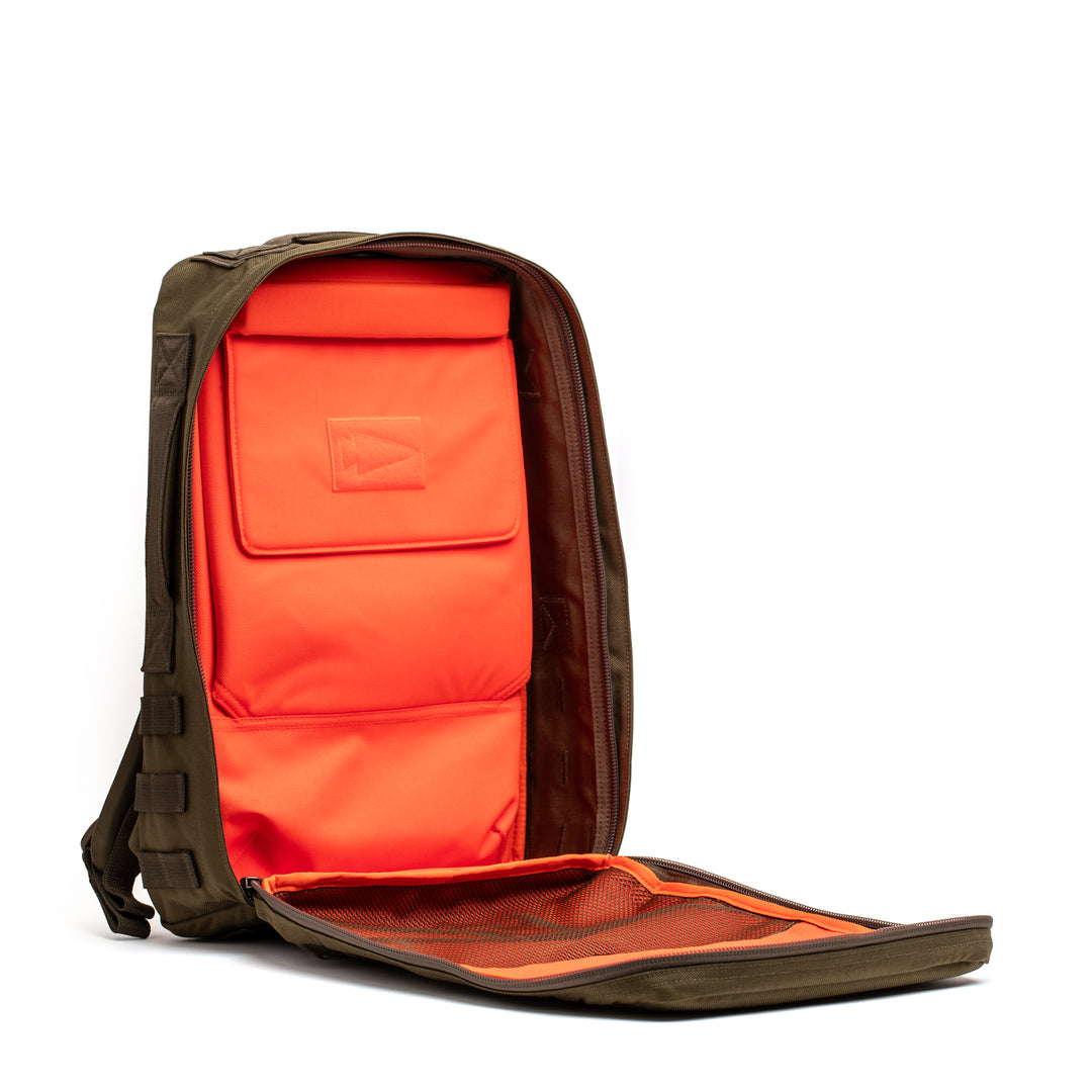 The GORUCK Rucker 4.0 is a khaki backpack with a front zipper, featuring a bright orange inner compartment and mesh pocket—perfect for organizing and carrying your essential rucking gear.