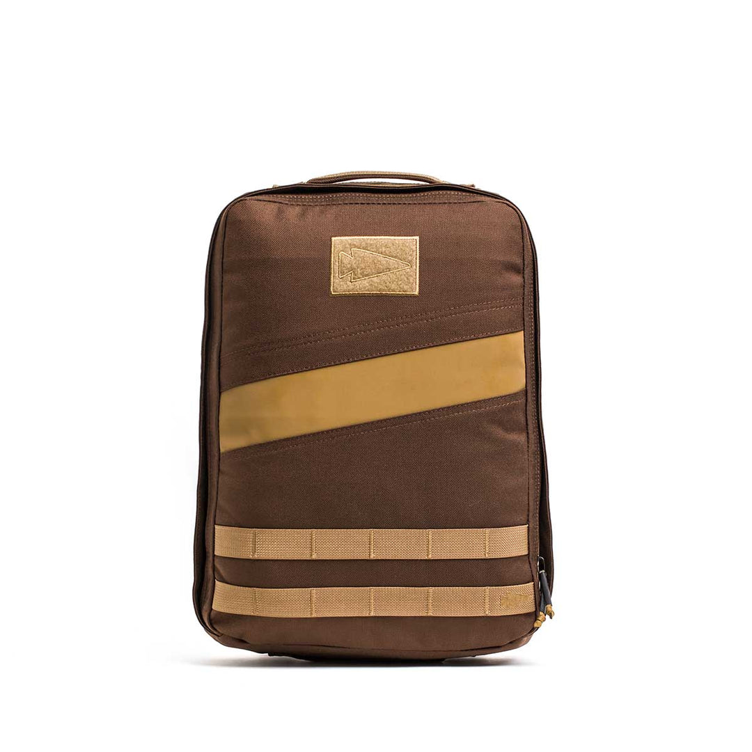 The GORUCK Rucker 4.0 is a brown and tan backpack with a top handle, diagonal stripe, and two horizontal bottom straps—perfect for carrying your essentials in style.