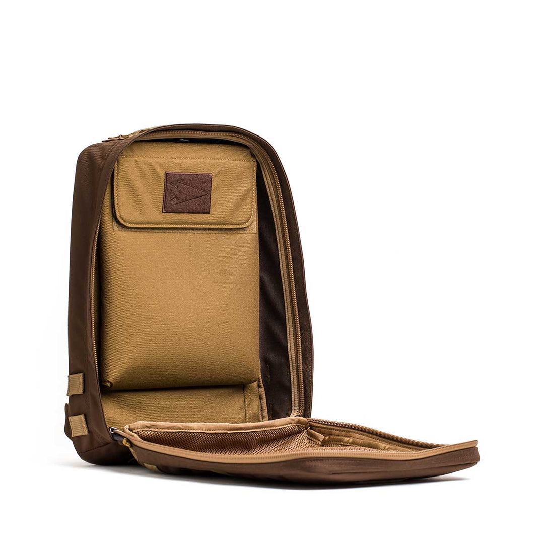 The GORUCK Rucker 4.0 stands upright with its main compartment unzipped, showcasing a simple tan interior.