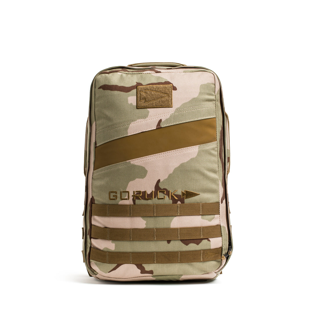 The GORUCK Rucker 4.0 is a tan and brown camouflage backpack featuring the "GORUCK" logo on the front, shown from the front view.