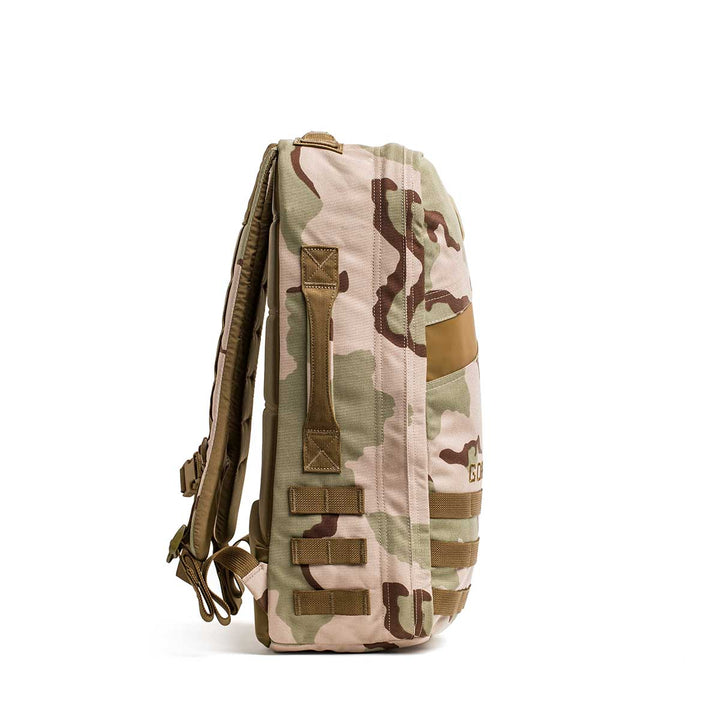 The GORUCK Rucker 4.0, a tan and brown camouflage rucking backpack, stands upright in a side view against a white background.
