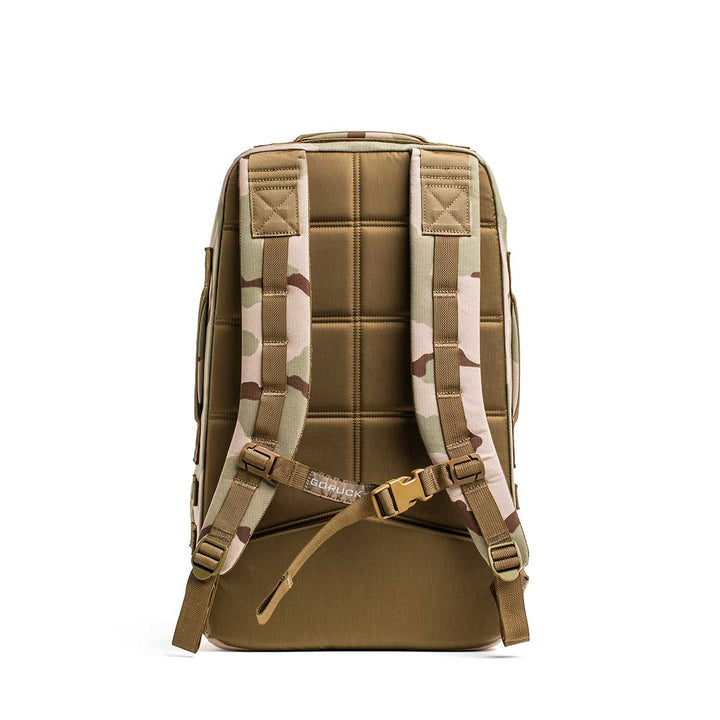 The GORUCK Rucker 4.0, shown from the back, is a tan fitness rucksack featuring padded shoulder straps and camouflage accents.