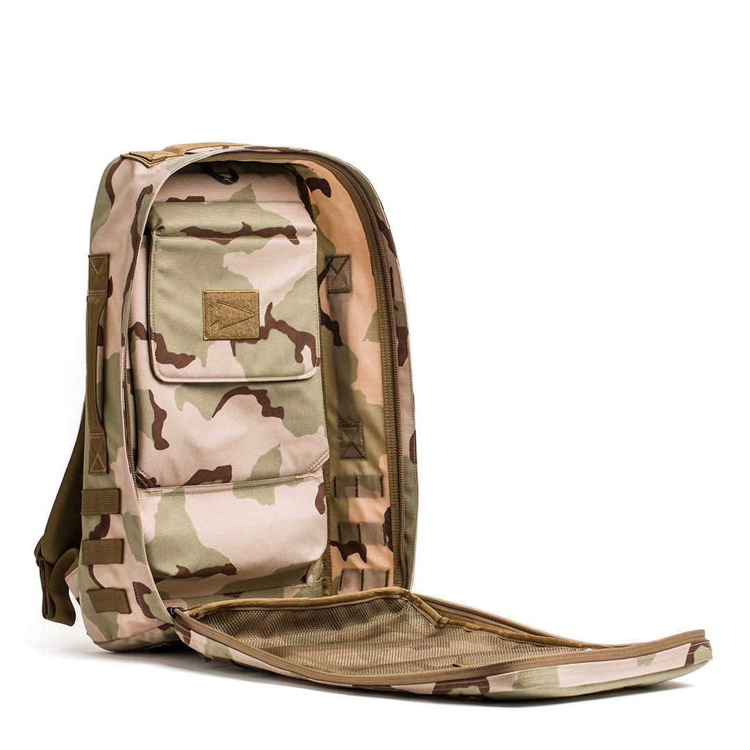 The GORUCK Rucker 4.0 backpack in tan and brown camouflage is shown unzipped, highlighting its spacious inner compartments and pockets.