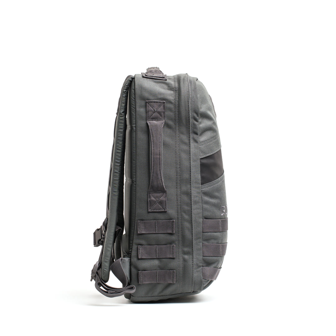 Side view of the GORUCK Rucker 4.0, a gray backpack featuring multiple straps and handles, displayed against a white background.