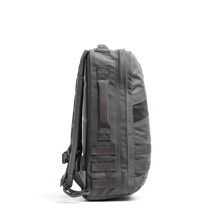 Side view of the GORUCK Rucker 4.0, a gray backpack featuring multiple straps and handles, displayed against a white background.