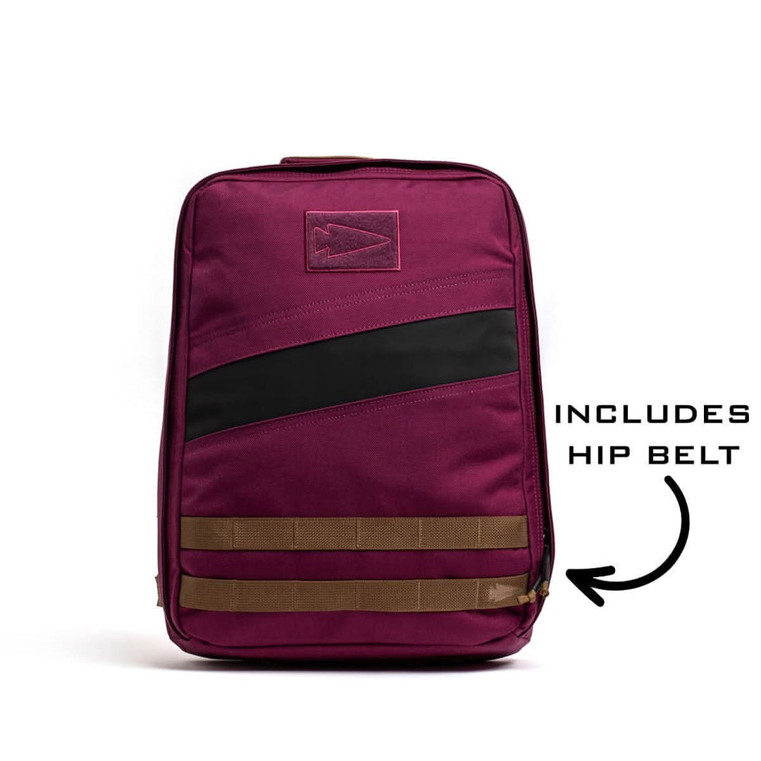 The GORUCK Rucker 4.0 rucksack features maroon fabric with black and brown accents, a front pocket, and comes equipped with a hip belt.