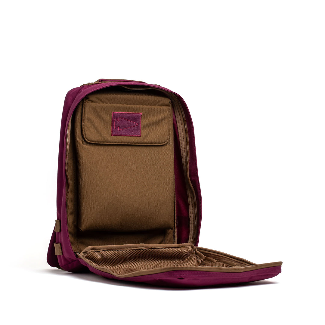 A maroon and brown GORUCK Rucker 4.0 rucksack sits open against a white background, showing its empty interior compartments.