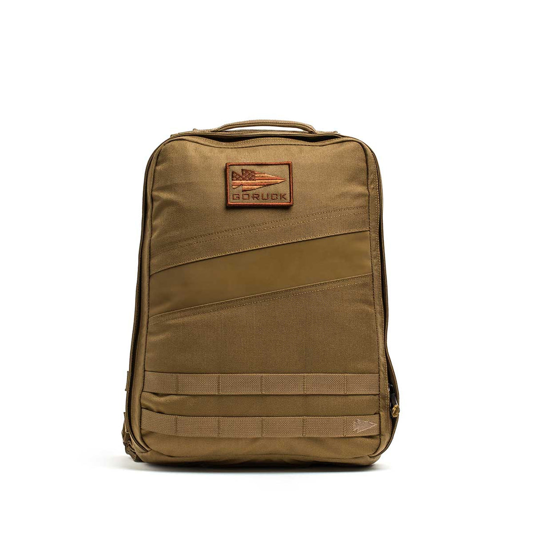 The GORUCK Rucker 4.0 is a tan tactical backpack with a top handle, patch, multiple compartments, and zippers—ideal for rucking or carrying Ruck Plates on any adventure.