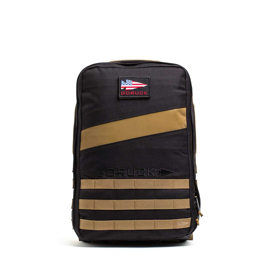 The GORUCK Rucker 4.0 backpack in black and tan features a patch and horizontal straps, ideal for rucking, shown against a white background.