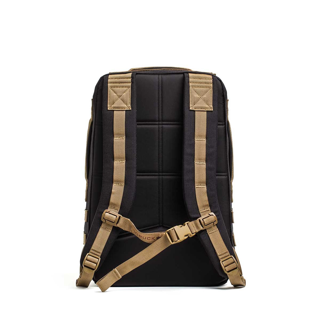 The GORUCK Rucker 4.0 is a black rucking backpack with tan padded shoulder straps, a chest strap, and space for ruck plates, shown from the back against a white background.
