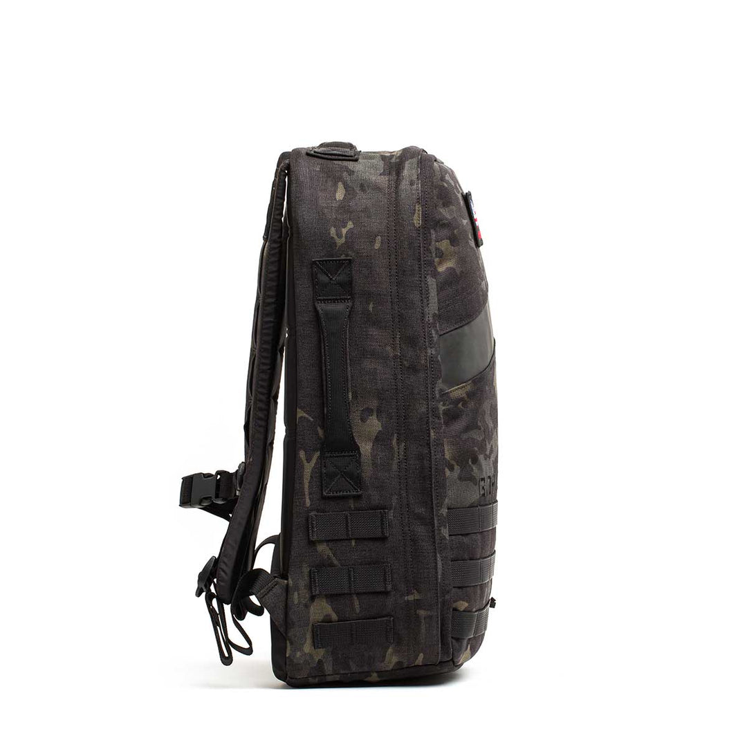 Side view of the GORUCK Rucker 4.0, a black and gray camouflage rucksack with straps and webbing, ideal for rucking, displayed on a white background.